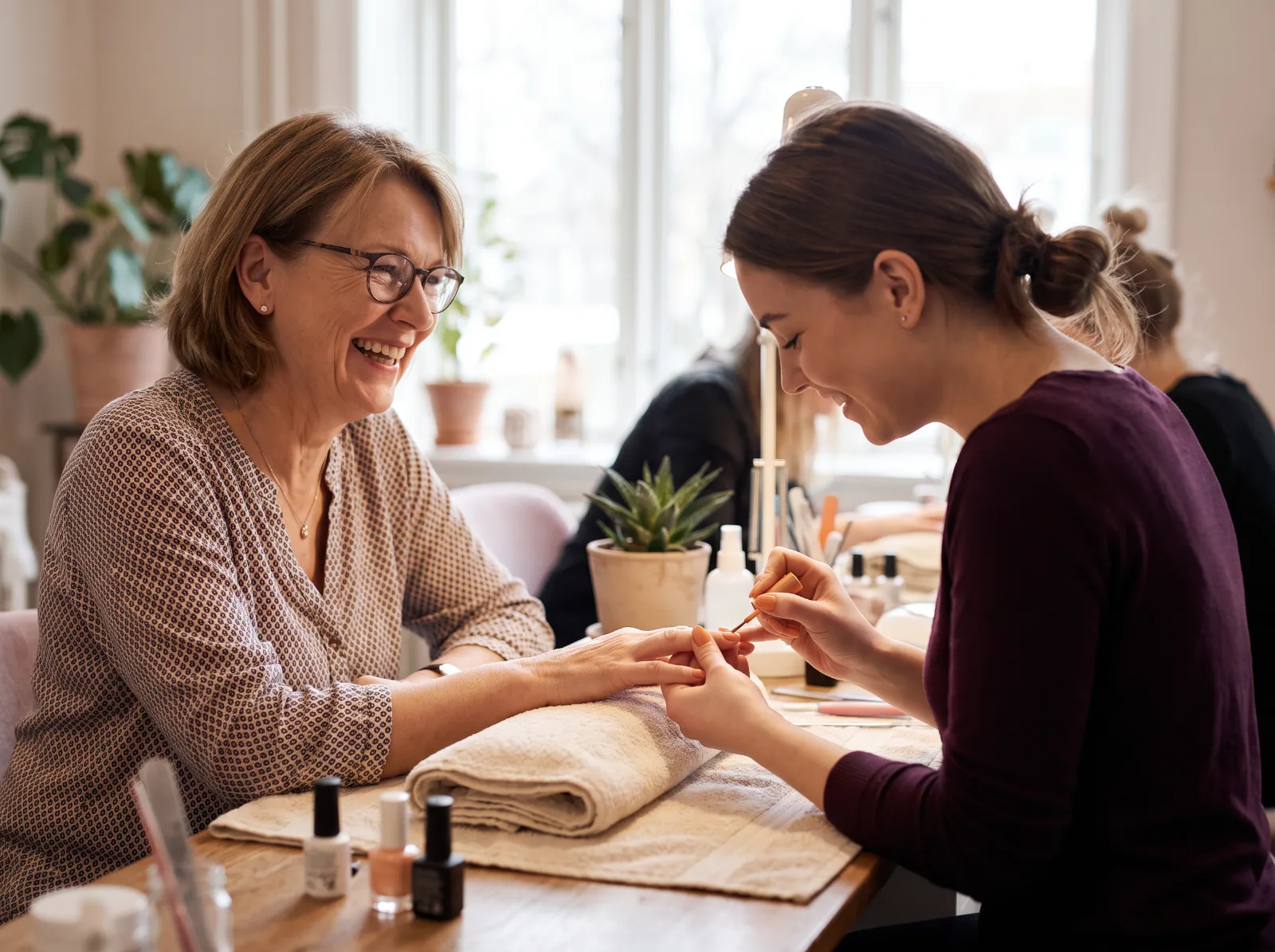 Nageldesignerin und Kundin lachen gemeinsam am Maniküretisch